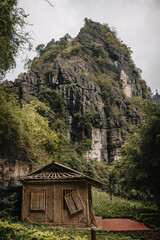 Ninh B&igrave;nh, Vietnam - March 3rd, 2020 : a decaying wooden hut and a karst mountain in the background 