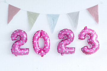 Pink party balloons 2023 numbers shape and cute triangle bunting flag over white wall texture background, happy new year 2023 - Powered by Adobe
