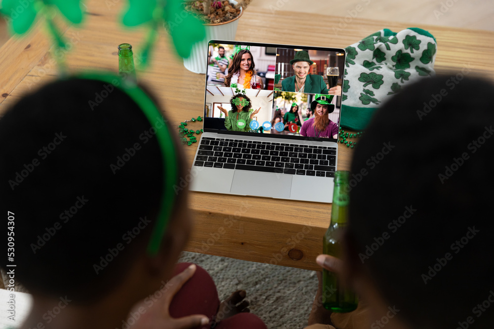 Sticker African american couple making st patrick's day video call to friends on laptop at home