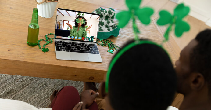 African american couple making st patrick's day video call to friend in costume on laptop at home