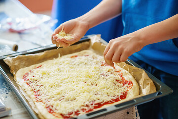Kid make pizza for dinner, hands add cheese. Healthy food for family lunch. Boy helping.