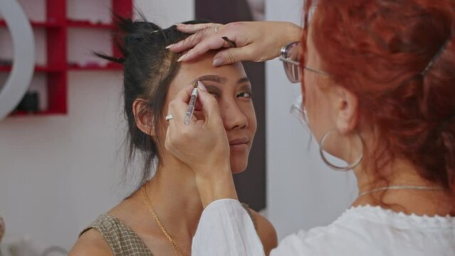 happy vietnamese woman stylist and european woman makeup artist are working on creating an image for. close-up. Asian woman and work as a stylist.