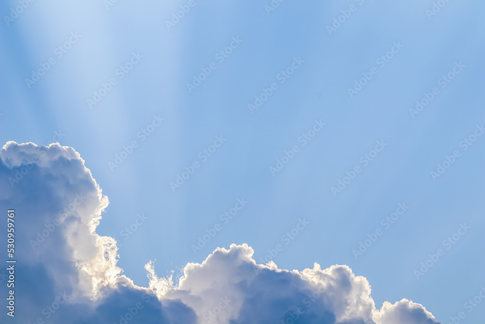 Wall mural background from blue sky with sun rays across clouds