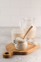 Fototapeta na wymiar A jar of raw rice and rice milk in a glass on a plank. Healthy food concept, alternative milk.