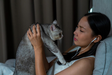 White tabby cat comforting his owner while she crying. Loneliness young Asian woman sitting on...