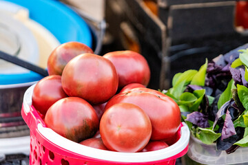 Selling ripe tomatoes and basil at a street bazaar. Fresh ripe vegetables grown on a farm on a small counter.