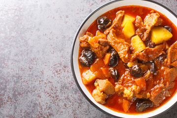 Spicy lamb stew with prunes, tomatoes, potatoes and saffron close-up on a plate on the table....