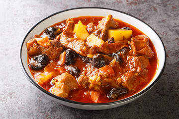 Khoresht Aloo Stewed lamb meat with dried plums or prunes, tomato, onion, potato, carrot and garlic closeup in the bowl on the table. Horizontal