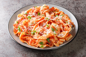 Italian pasta food homemade pappardelle with with bacon and tomato, parmesan cheese and chopped parsley closeup in the plate on the table. Horizontal
