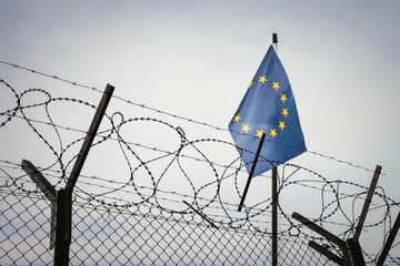 View of European union flag behind barbed wire against cloudy sky. cancel culture Russia in world....