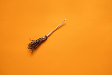 witch's broom on an orange background with a place for text, the concept of a creative happy Halloween