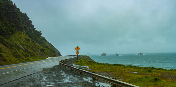 a road leading out into the distance with a view of the ocean on a dreary day