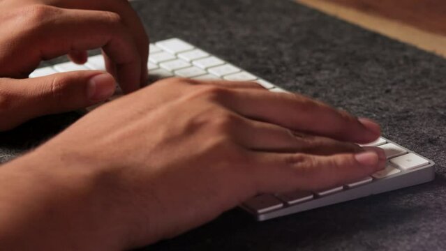 Male latino hands typing fast ina white wireless keyboard using all his fingers