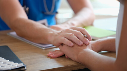 Psychologist or gynecologist holds hands of a female patient and provides professional...
