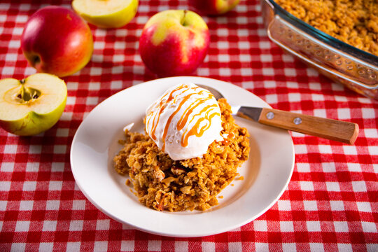Homemade apple cramble crisp cake on white plate with autumn leaves on the background