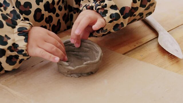Close up of little girl modeling the clay in leopard jacket.