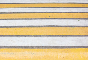 Yellow and white stripes on a pedestrian crossing.