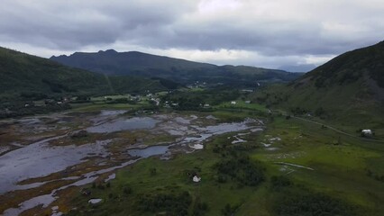 Aerial view of a small township with isolated houses in a boggy valley basin in Norway.