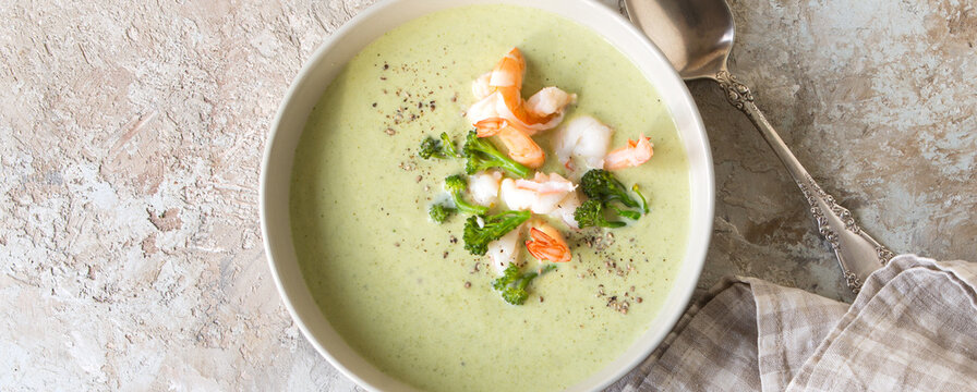 a bowl of creamy broccoli soup with shrimp on a light table