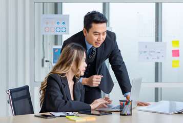 Millennial Asian successful professional male businessman mentor in formal suit coaching training helping female businesswoman secretary trainee working with laptop computer in office meeting room