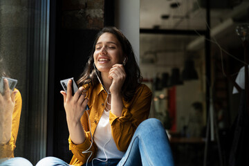 Young woman sitting and listening the music. Portrait of happy woman listening music with earphones...