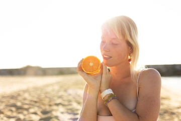 Cheerful young woman enjoy at tropical sand beach. Portrait of happy girl with fruit. Young woman having a picnic on the beach.