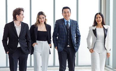 Full body shot of Millennial Asian successful professional male businessmen and female businesswomen in formal suit smiling posing look at camera walking side by side together in company hallway