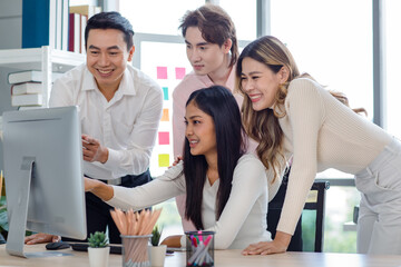 Millennial Asian beautiful successful professional businesswoman sitting smiling pointing finger showing data information on computer monitor to male businessmen female colleague in company office