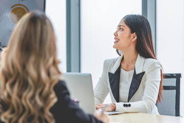 Fototapeta premium Closeup shot of Millennial Asian beautiful successful professional female businesswoman employee in formal suit sitting smiling talking to colleagues at working desk in company office meeting room