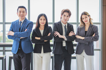 Millennial Asian successful professional male businessmen and female businesswomen colleagues standing side by side smiling laughing posing gesturing together in company office meeting room.