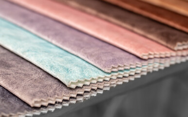 Fabric texture close up. Fabric swatches in different colors are stacked for selection. A variety of shades of upholstery material for furniture and interior. A set of multi-colored rolls of material.