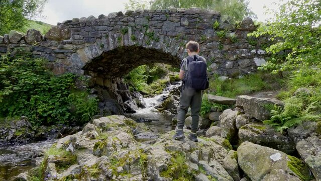 Boy standing at Ashness Bridge is an old packhorse bridge with wonderful views looking back towards the lake.it is probably the most photographed,and very popular with visitors.