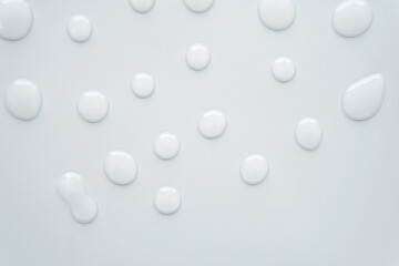 Flatlay top view transparent serum or gel texture drop round shape on plain light white grey background and space. Skincare ingredient suitable for acne prone oily sensitive or all skin types