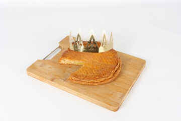 frangipane king cake with crown on a wooden board on white background 