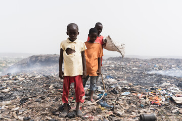 Sleazy, unkempt boys hanging around in an African garbage dump in search of things to eat and sell