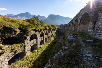 Fototapeta na wymiar View of Fort Variselle at Lake Montcenis (Moncenisio) on the border between Italy and France. Old ancient historical fort ruins in stone in the Alps mountains