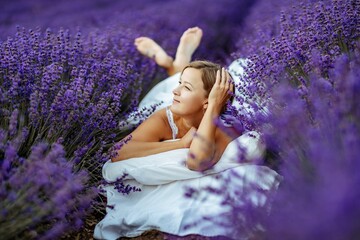 A middle-aged woman lies in a lavender field and enjoys aromatherapy. Aromatherapy concept, lavender oil, photo session in lavender