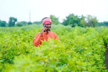 Indian farmer talking on smartphone at agriculture field.