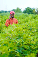 Indian farmer talking on smartphone at agriculture field.