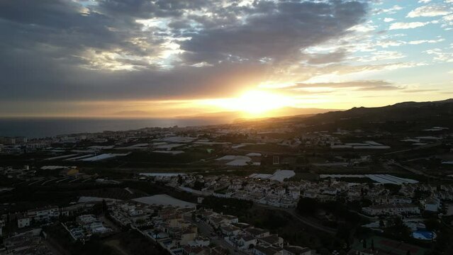 camera rising up over countryside with beautiful sunset and clouds in the distance.