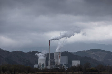 Overcast grey sky and toxic emissions released from a coal power station chimney. Energy industry, environmental and health issue concept.