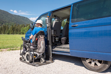 Young Caucasian man in a wheelchair using the vertical platform lift to get in the van parked in the nature © 24K-Production