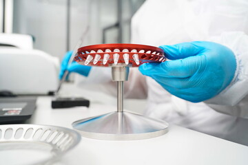Almaty, Kazakhstan - 08.15.2022 : A laboratory assistant puts plastic flasks for PCR into a round centrifuge.