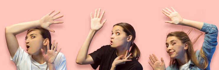 Shocked faces of young gils looking through glass isolated over pink background. Models leaning...