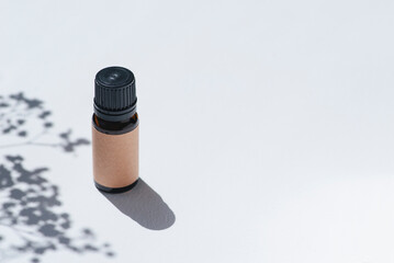 Amber bottle with craft label and essential oil. White background with daylight and beautiful shadows. Skincare products, natural cosmetic. Beauty concept for face and body care