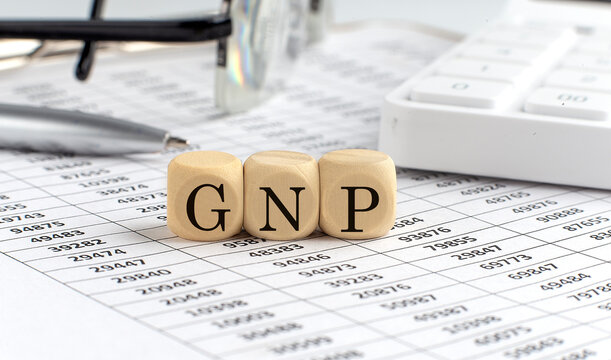 wooden cubes with the word GNP on a financial background with chart, calculator, pen and glasses, business concept.