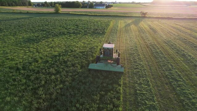 In Door County, WI, a farmer on a John Deere tractor, cuts his alfalfa field in late August.