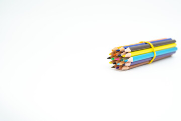 wooden colored pencils gathered in a bundle with a rubber band on a white background with a point (lead) in focus