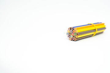 wooden colored pencils gathered in a bundle with a rubber band on a white background with end part in focus