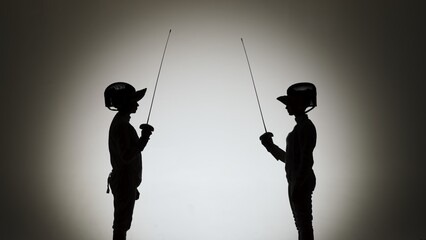 Side view of black silhouettes two young female swordswoman saluting with rapiers. Athletes in white uniforms and helmet pose in dark studio with backlight. Girls holding epees in their hands.